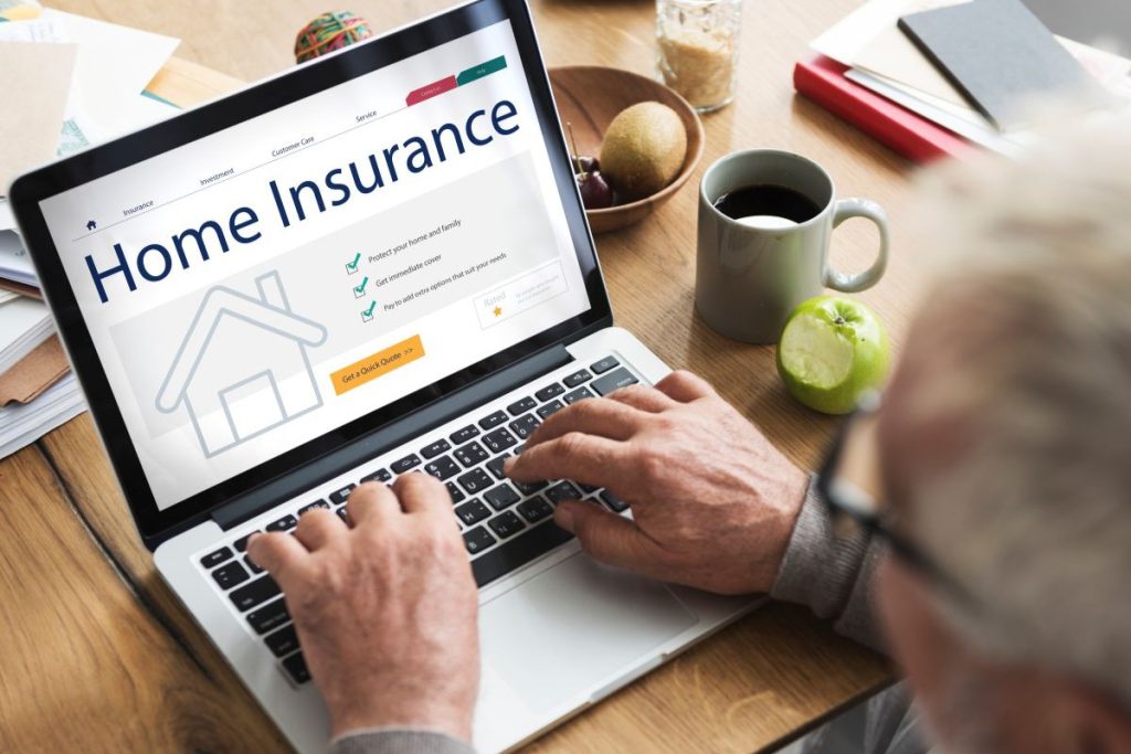 Mężczyzna przeglądający na laptopie ofertę na ubezpieczenia majątku, z widocznym formularzem wyceny polisy domowej na ekranie.